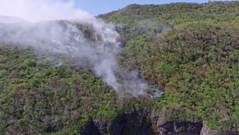 Toma-Aérea-Acercándose-A-Una-Selva-Tropical-En-Llamas-En-Un-Parque-Nacional-Con-Humo-En-Aumento