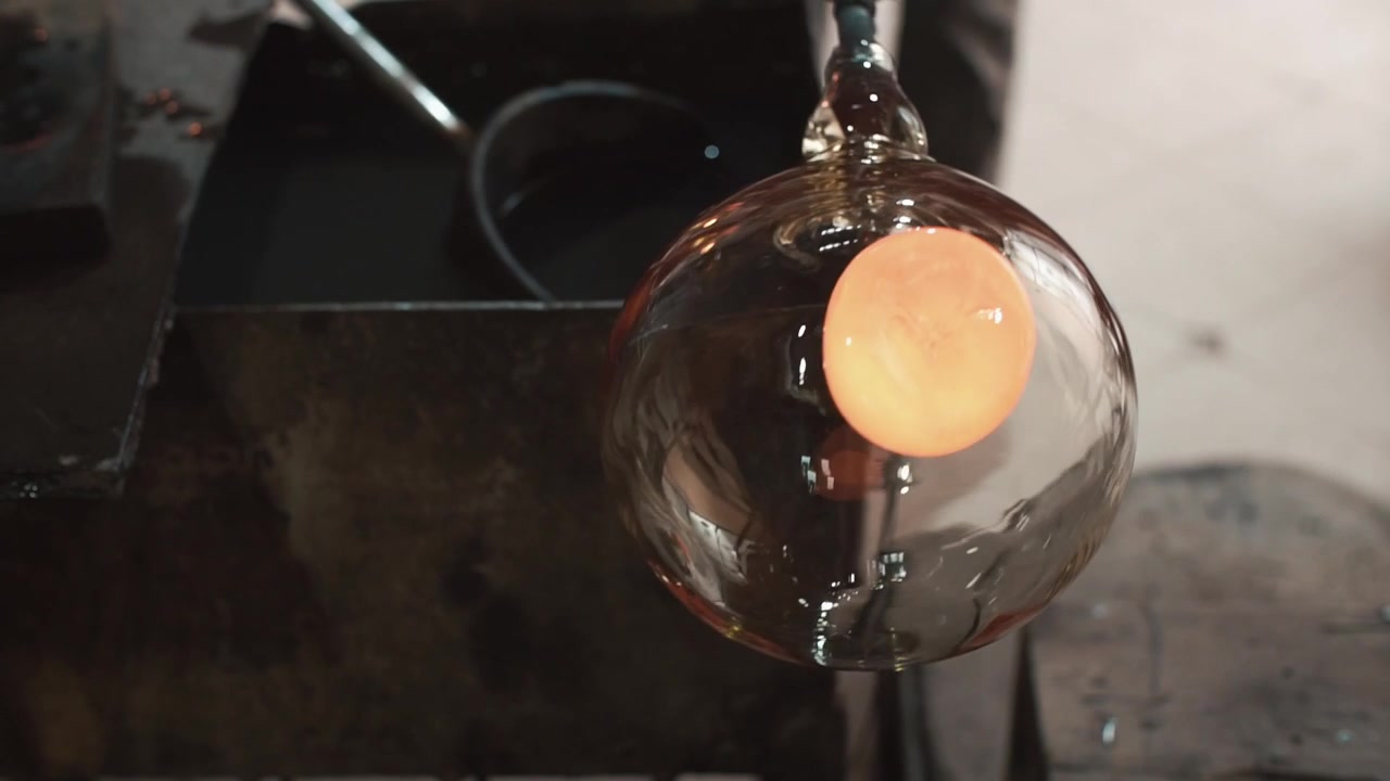 Souffleur de verre façonnant une sphère de verre en fusion avec des pinces
