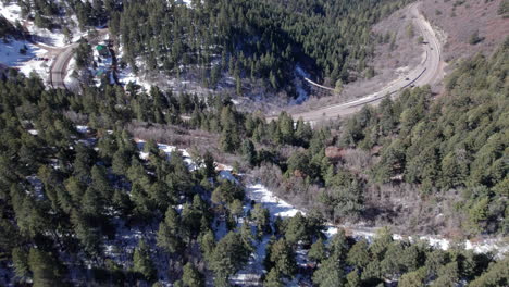 Vista-Aérea-Volando-Sobre-Una-Carretera-Rural-De-Montaña-Y-Un-Valle-Cubierto-De-Nieve