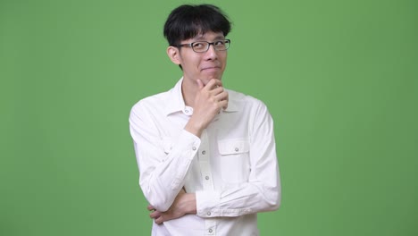 젊은 행복한 아시아 사업가 생각하면서 웃고