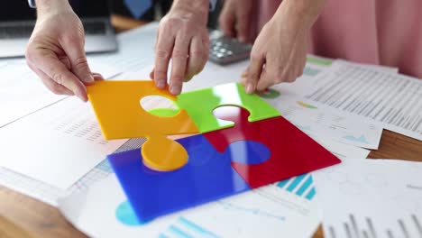 business people putting together colorful puzzle at table in office closeup 4k movie slow motion