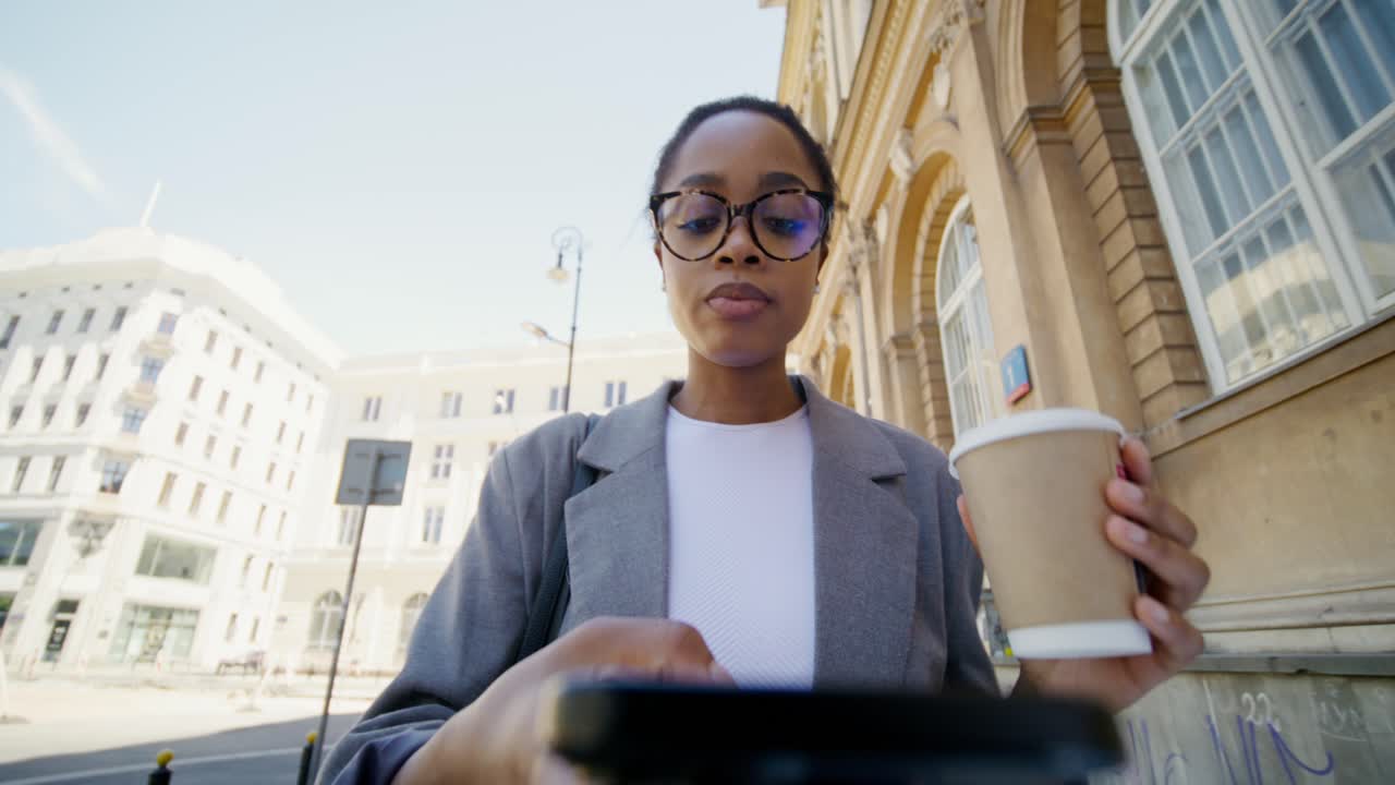 Businesswoman using smartphone while walking on city street
