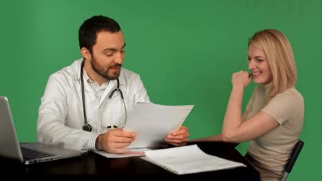 smiling doctor read medical history of young woman at hospital on a green screen, chroma key