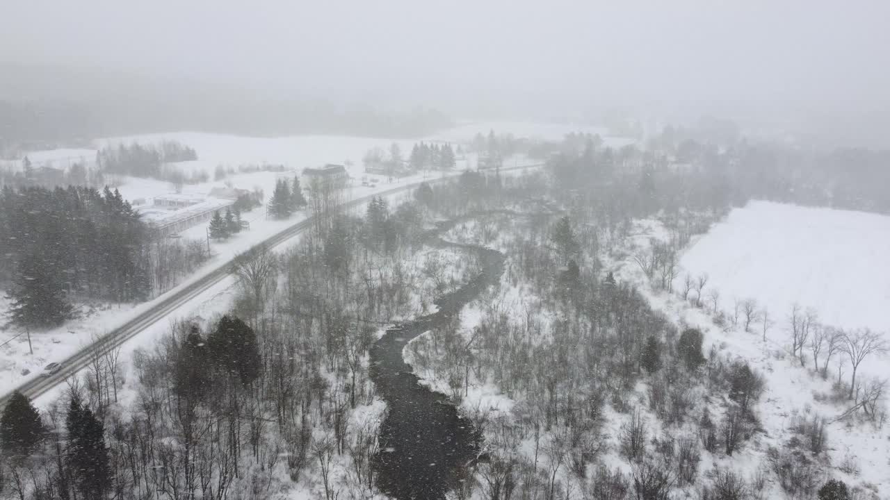 Aerial View of a Snowy Landscape during a snow storm with a Meandering River