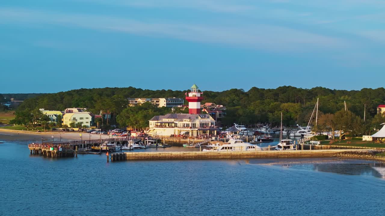 Wide panoramic establishing of marina harbor and lighthouse in soft afternoon lighting, Harbour Town Pier South Carolina USA