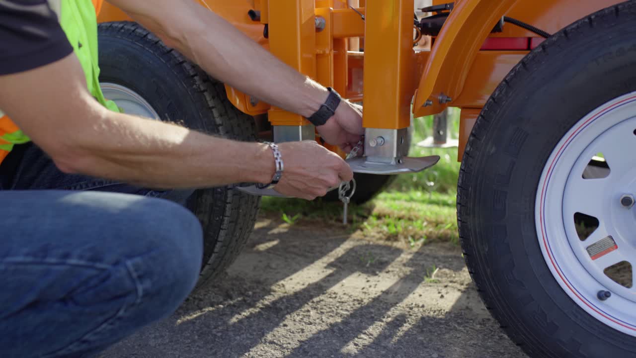 un trabajador de la construcción en un chaleco de seguridad amarillo desbloquea el lugar de la base de metal de una señal de parada móvil