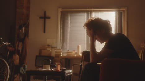 vulnerable young man, full of sadness, praying to god in living room