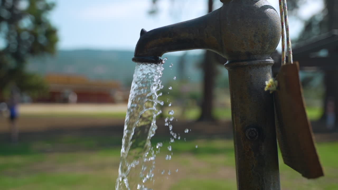 el agua sale de un grifo antiguo en un parque al aire libre en un día de verano