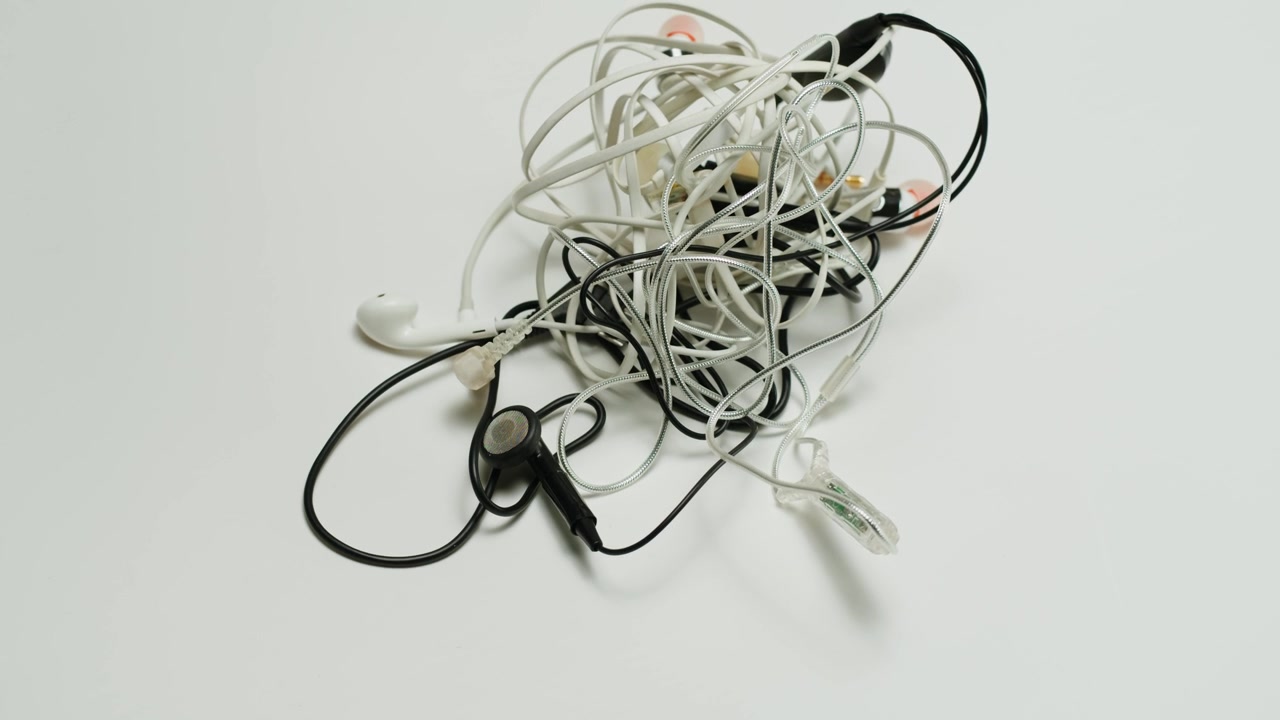 Untangle the headphones close-up. Tangled wires on table. Trying to untangle many messy cables