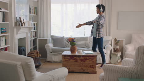 Un-Joven-Feliz-Bailando-En-Casa-Celebrando-El-éxito-Escuchando-Música-Usando-Audífonos-Divirtiéndose-Bailando-En-La-Sala-De-Estar-El-Fin-De-Semana