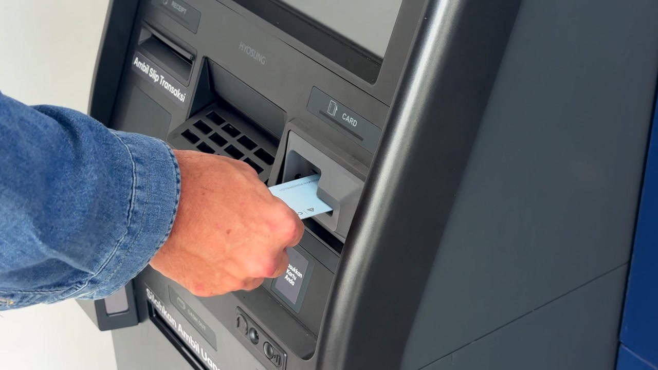 Persona che inserisce la carta bancomat nello sportello automatico