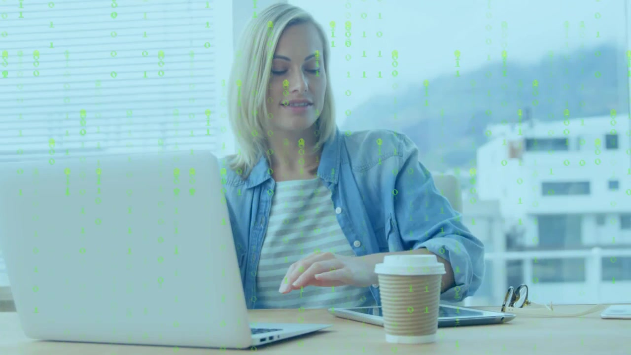 Donna che lavora su laptop e tablet in un ufficio moderno con sovrapposizione di dati digitali