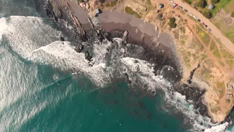 Aerial-descend-of-coast-with-waves-crashing-against-the-rocks-and-beach,-Pichilemu,-Chile-4K