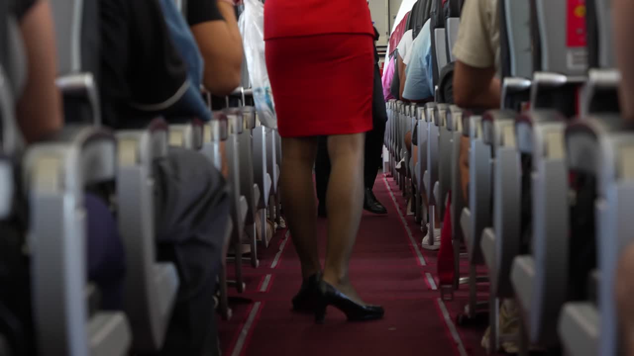 vista media de una azafata o asistente de vuelo en traje rojo sosteniendo una bolsa de basura opaca