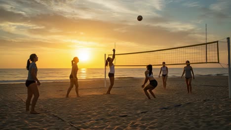 women playing beach volleyball at sunset