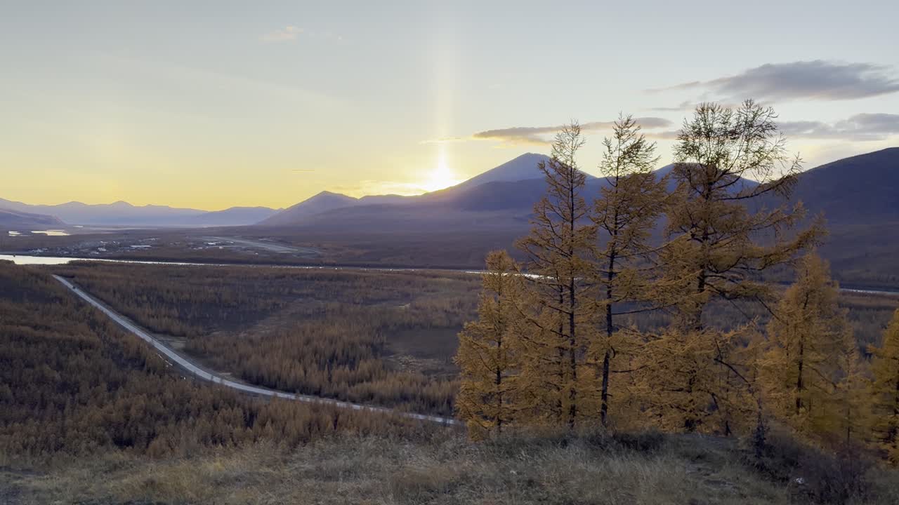 Golden autumn road leads to distant mountain sunset
