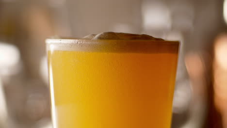 close up of craft beer ipa being poured in to a pint glass, light background