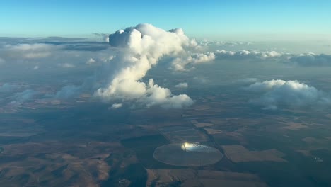 nice view from a jet cockpit of a tiny cumulus ahead overflying a rounded solar farm in andalucia, spain