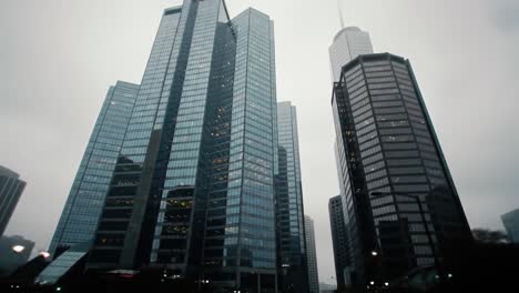 a foggy day envelops a bustling city as skyscrapers loom, obscured by mist. the atmosphere creates a mysterious and serene vibe, while urban activity continues below.