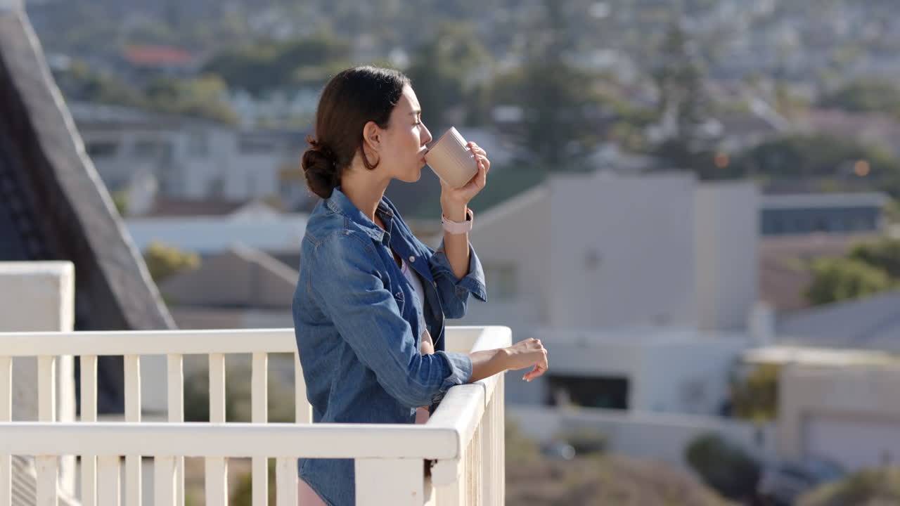 Woman enjoying morning coffee on balcony, looking at city view, copy space