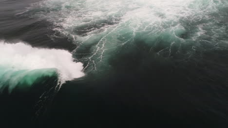 slow motion wave forms smooth arc before crashing under overcast skies