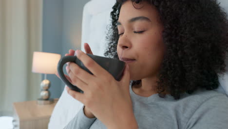 woman drinking a hot beverage in bed