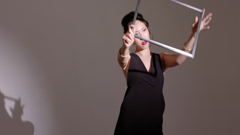 chinese woman in black dress responding to spotlight casting frame shadow, rotating frame in studio