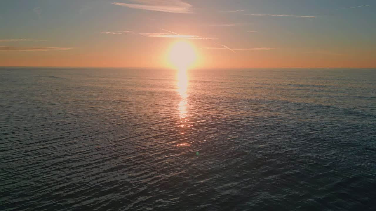 Sunrise sea surf reflecting sun washing beach drone view. Dawn sky over ocean