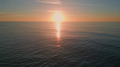Sunrise sea surf reflecting sun washing beach drone view. Dawn sky over ocean