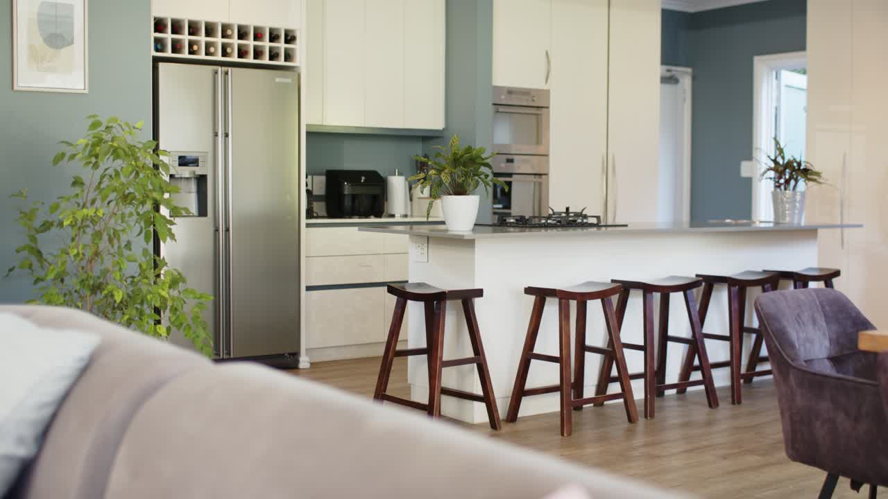 Camera starting to pan is sweeping open kitchen and island, revealing appliances and showing layout