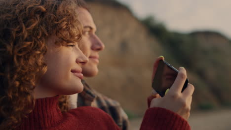 woman and man making picture on smartphone at beach. couple enjoying vacation