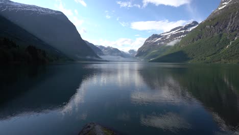 Fog-and-clouds-flying-over-calm-lake-in-Norway