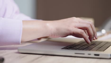 mano de cerca de una mujer de negocios escribiendo teclado computadora portátil en la oficina de escritorio