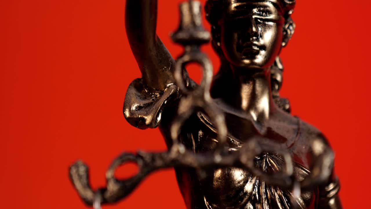 Primo piano della Statua della Giustizia con la bilancia su sfondo rosso