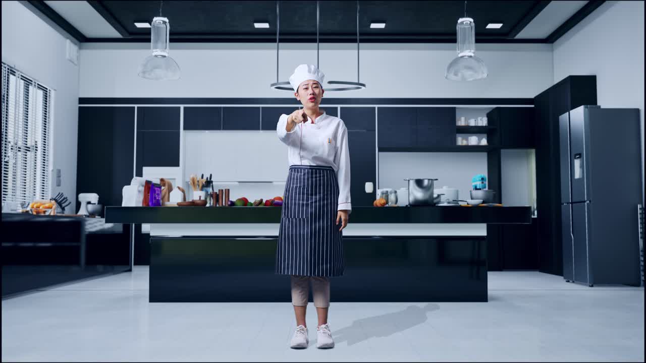 Figura intera di una chef asiatica che urla alla telecamera nella cucina di casa.