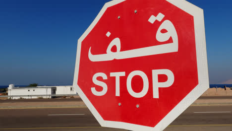 Slow-Panning-Shot---Arabic-Stop-Sign-in-front-of-Highway-Intersection