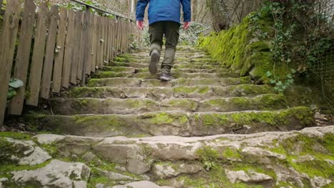 active senior man ascends a steep flight of old uneven stone steps outdoors