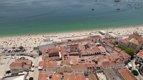 aerial backwards of a wonderful beach and the village behind. sesimbra, portugal. real time