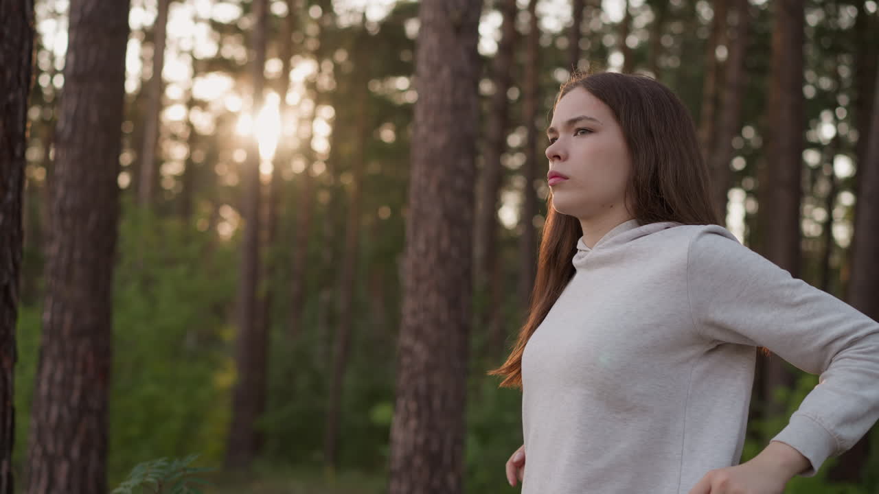 mujer gira los hombros haciendo ejercicio al atardecer. mujer joven realiza actividad de calentamiento preparándose para un entrenamiento de fitness de pie en el bosque de la noche