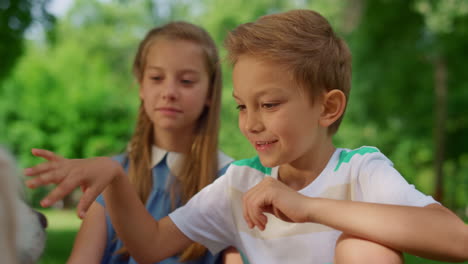 boy caressing white dog on picnic close up. children play with pet on nature.