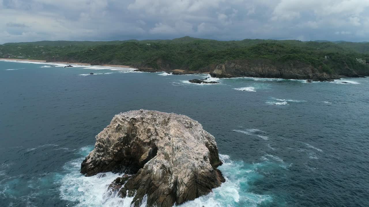 toma aérea de una gran formación rocosa y la costa de zipolite, oaxaca