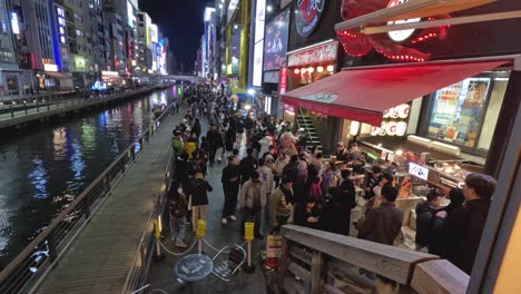 crowded walkway along an illuminated urban canal