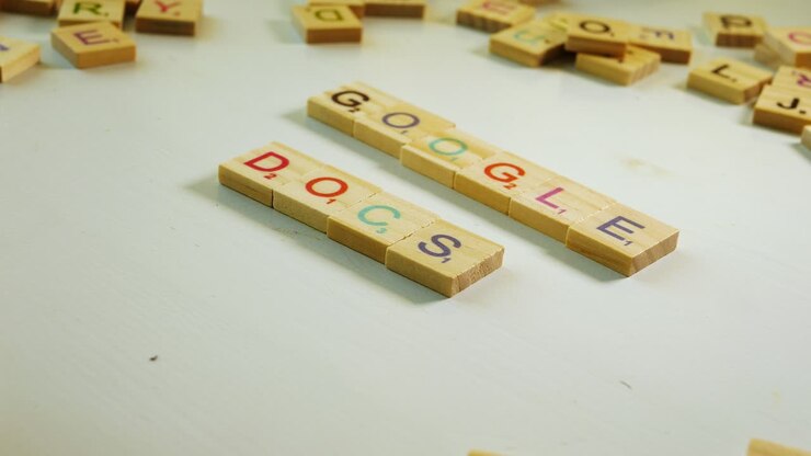 Un tavolo con lettere di legno sparse e una persona che compone Google Docs