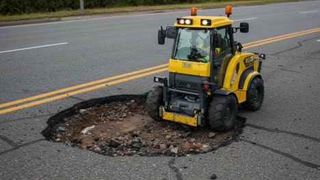 road repair work: heavy machinery filling a large pothole with dirt to restore surface integrity and ensure safe driving conditions