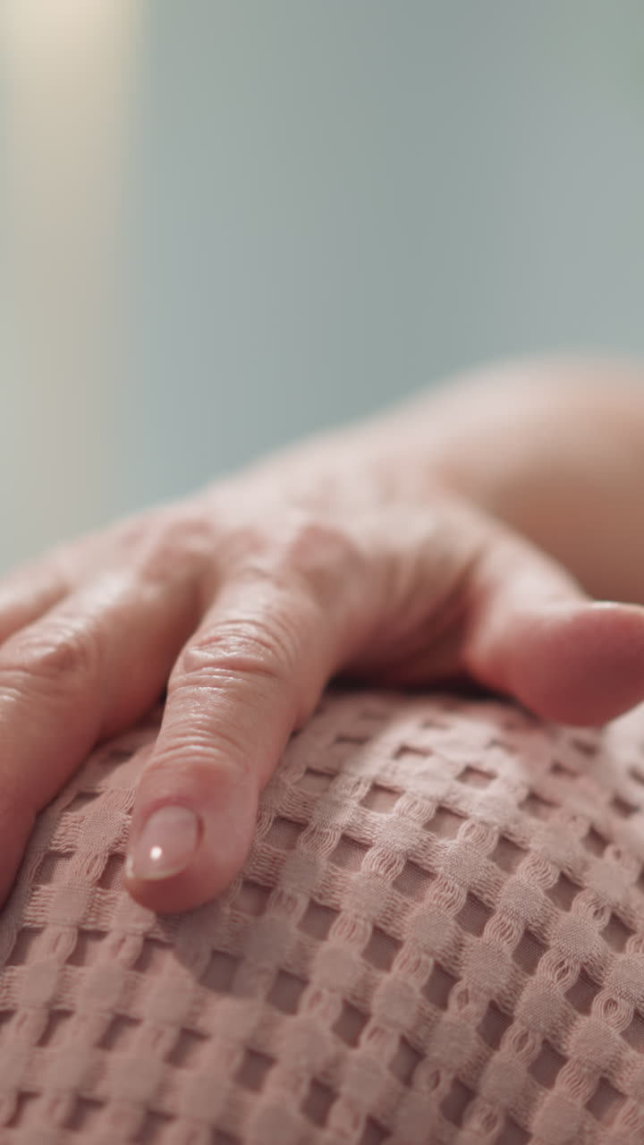 Wrinkled hand of old woman sitting with little boy on sofa in living room closeup. Grandmother spends time with grandchild at home. Family relationship