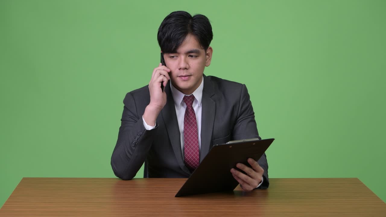 젊은 잘생긴 아시아 사업가 녹색 배경에 클립보드와 함께 작업