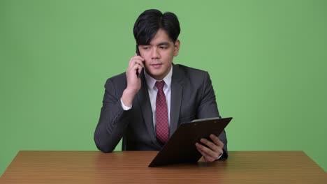 joven empresario asiático guapo trabajando con cartón contra fondo verde