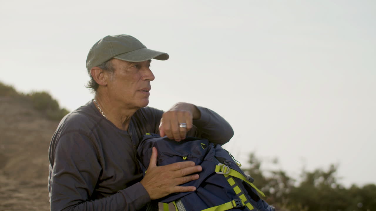 caminante masculino cansado sentado en el suelo y relajándose después de escalar