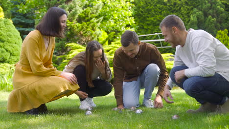 side view of a group of men and women friends calculating distance between petanque balls in the park