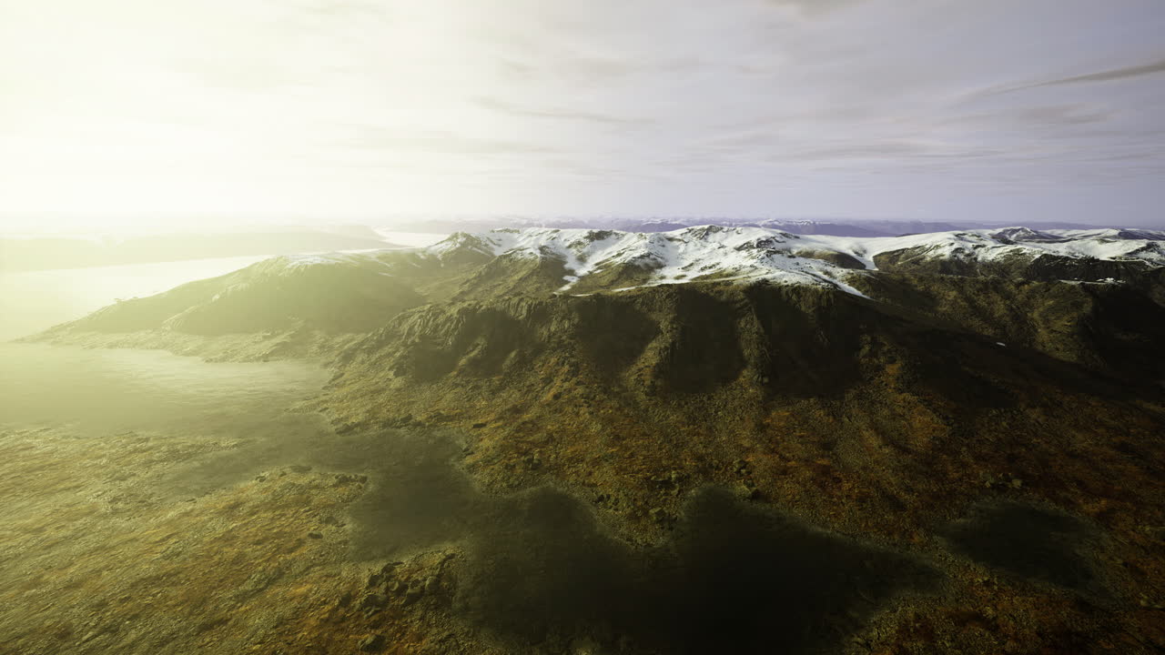 Mountain landscape at sunrise with snow capped peaks and misty valley
